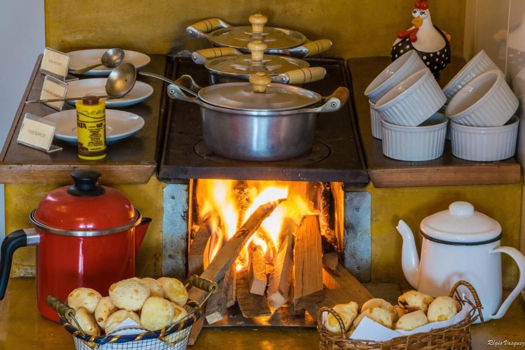 Fogão a lenha aceso com panelas e cestas de pão de queijo